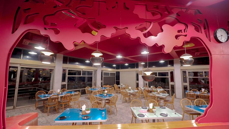 An image of a restaurant with tree cutouts on top and is also featuring tables and chairs at Pride Resort Ambaji